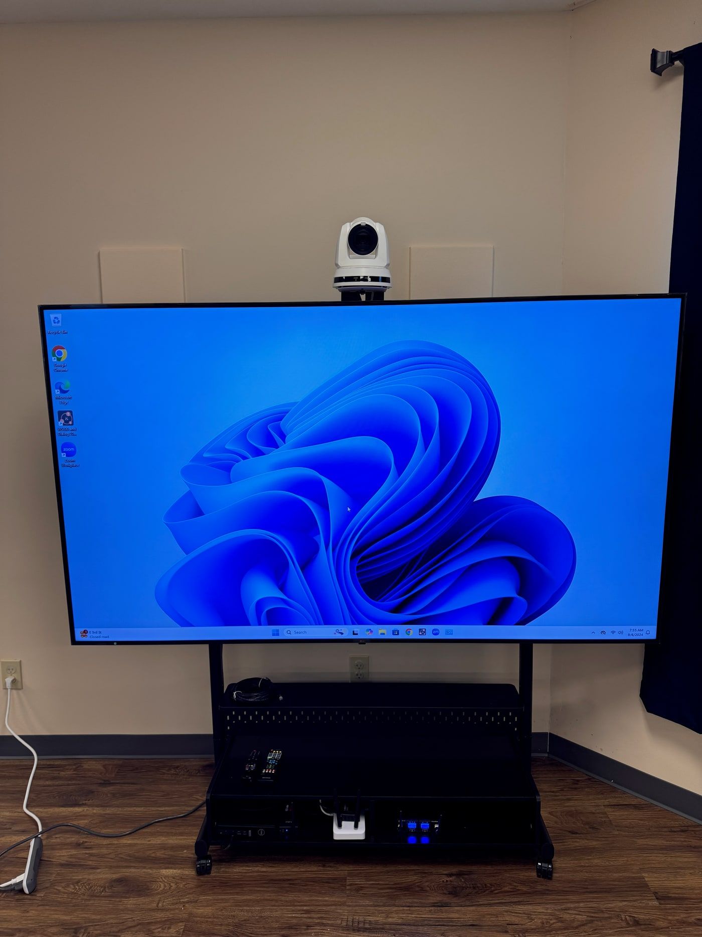 A television mounted on a rolling mobile cart, positioned for a conference room presentation.