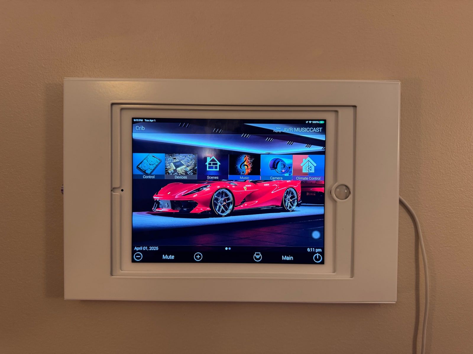 A wall-mounted URC touchscreen control panel showing a home automation menu with control, scenes, and camera options.